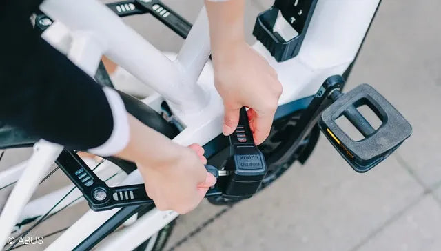 Person adjusting a bike lock on a bicycle