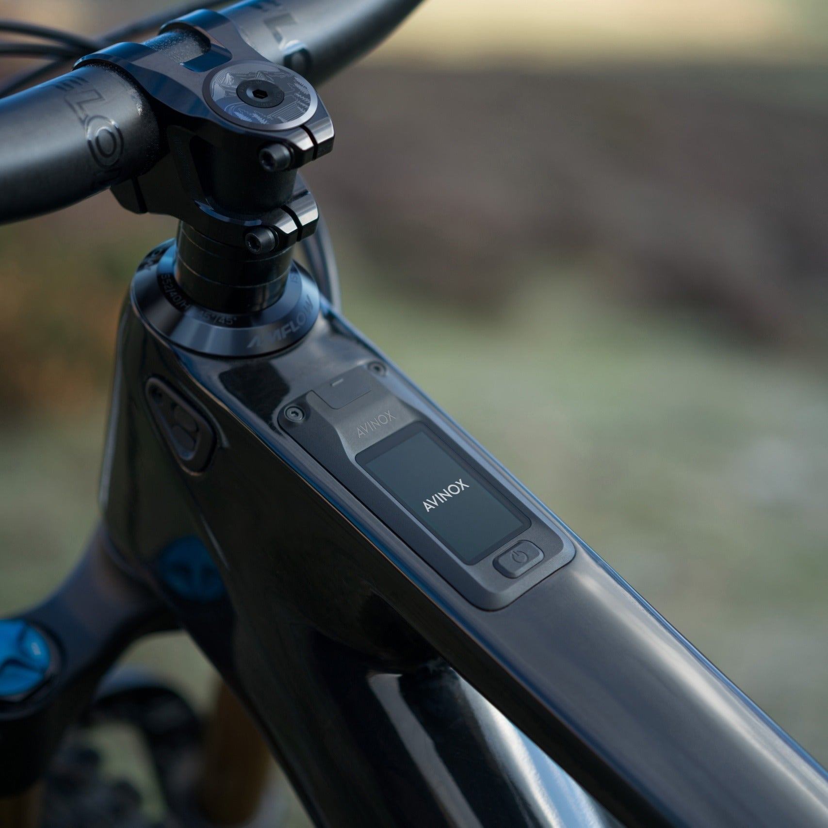 Close-up of a bicycle handlebar with Avinox control panel on a blurred natural background