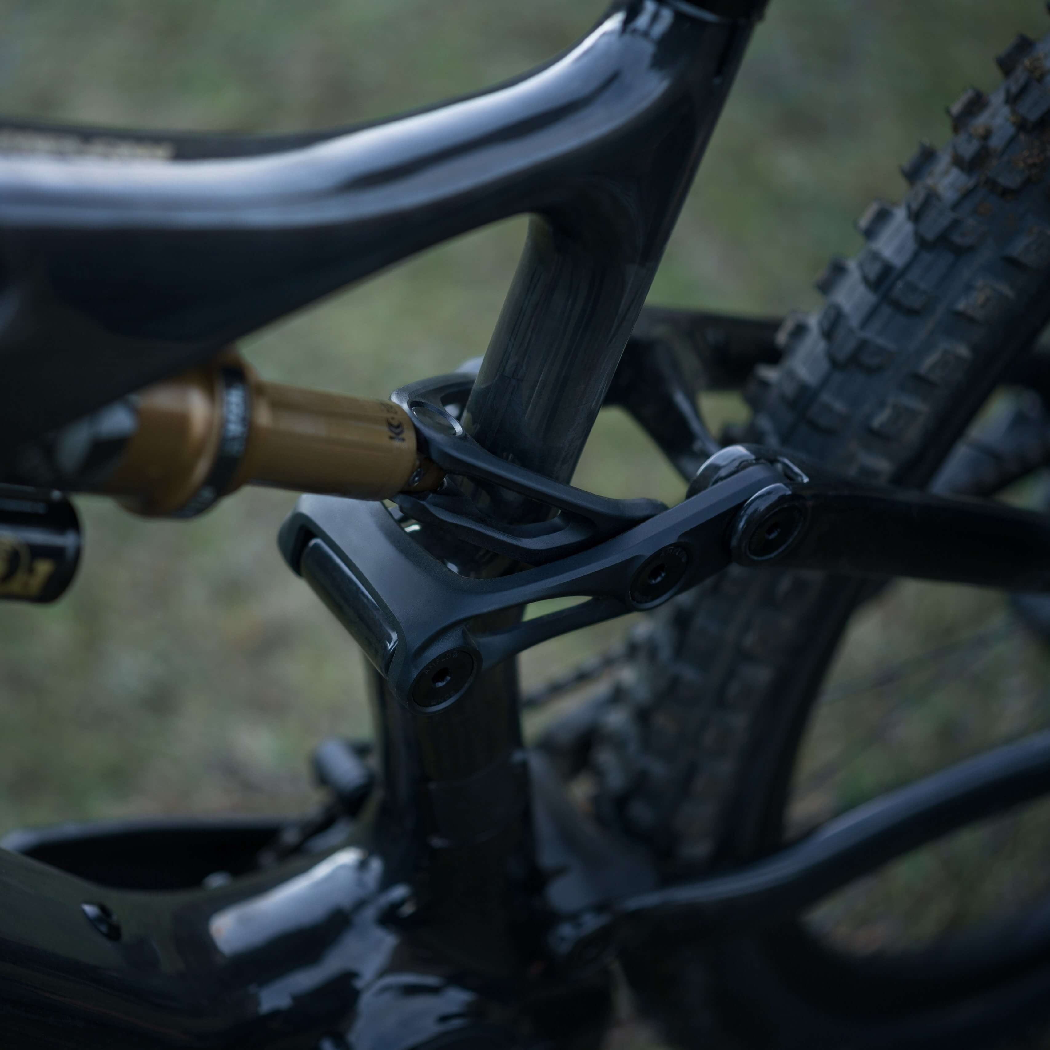 Close-up of a mountain bike's rear suspension shock with blurred grass background
