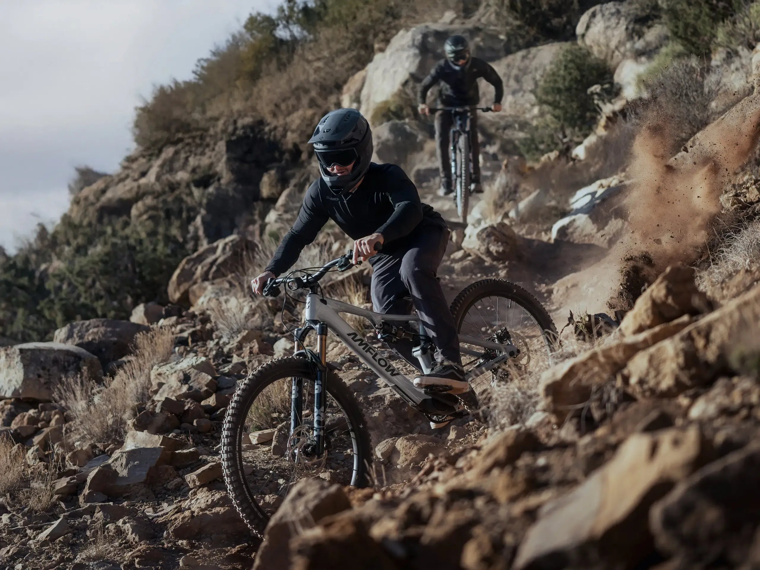 Two mountain bikers navigating a rocky trail on a mountain.
