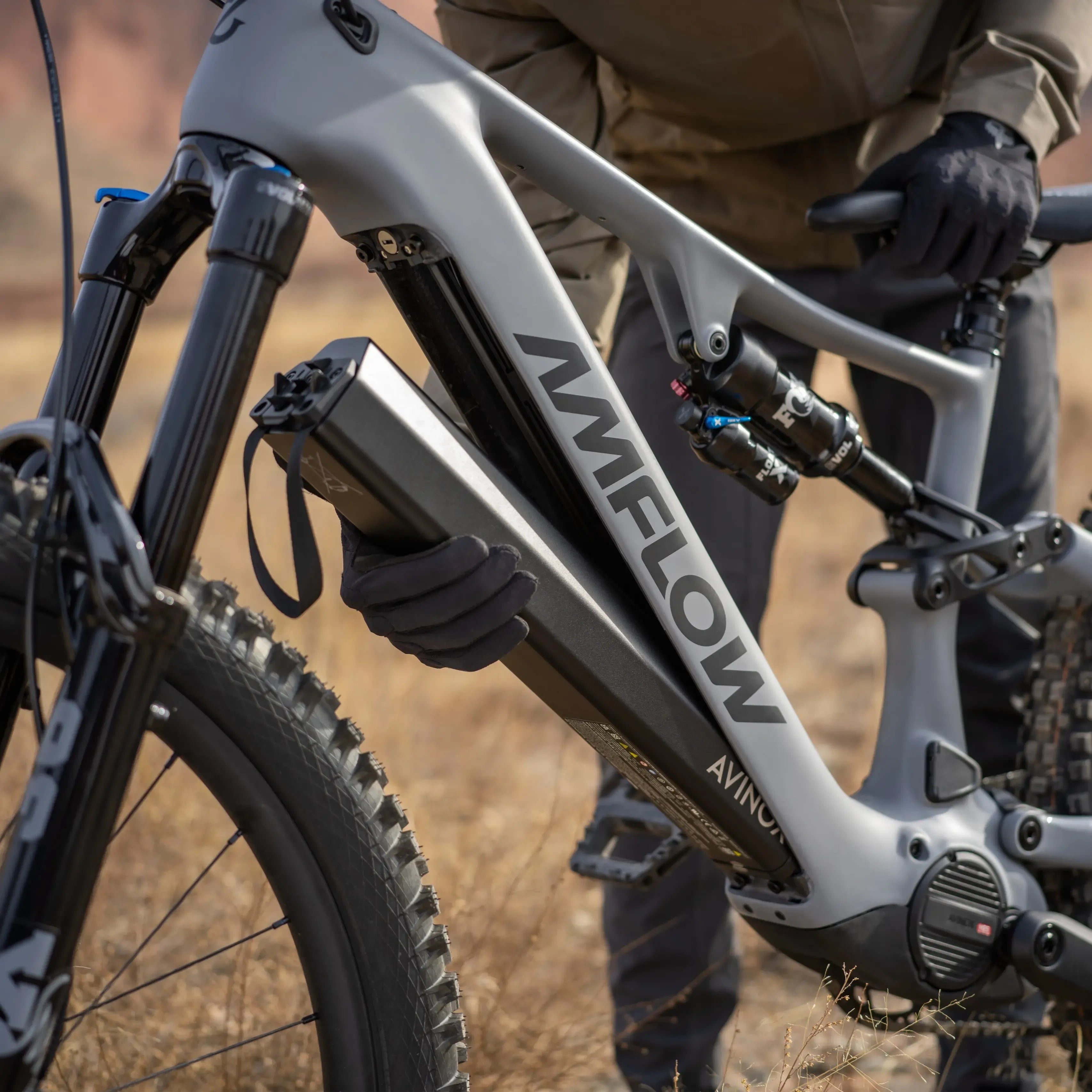 Close-up of someone removing a battery from an Amflow Electric Moutnain Bike in an outdoor setting.