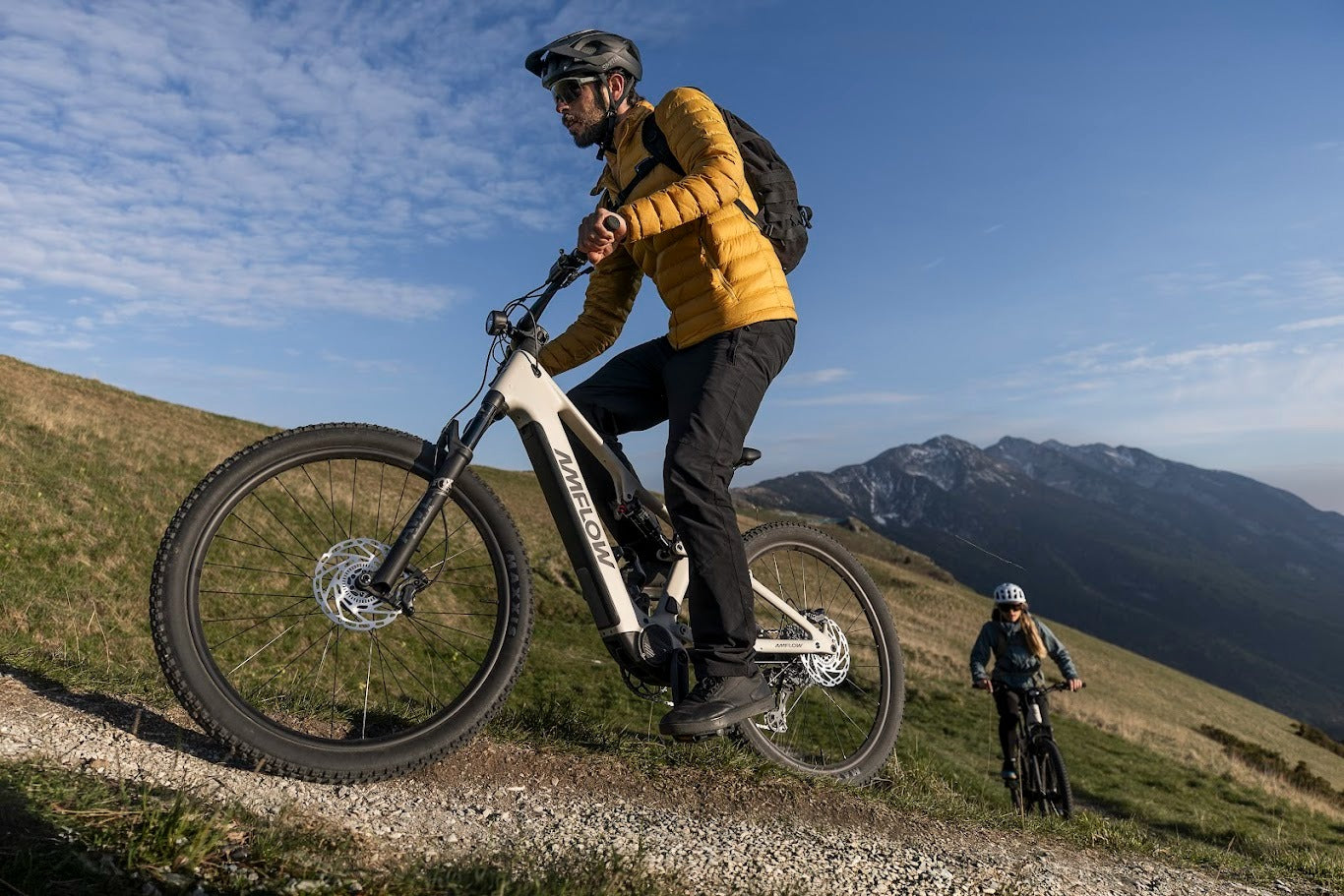 Person riding an Amflow mountain bike on a trail with mountains in the background
