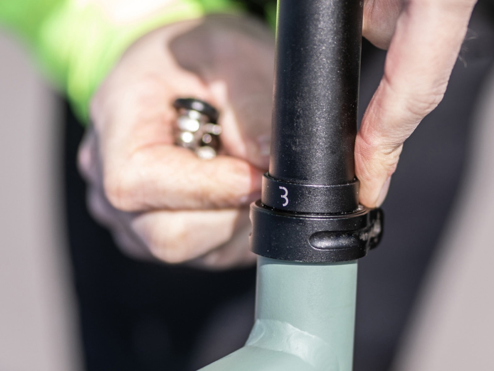 Close-up of a person adjusting a bicycle seat post with a blurred background