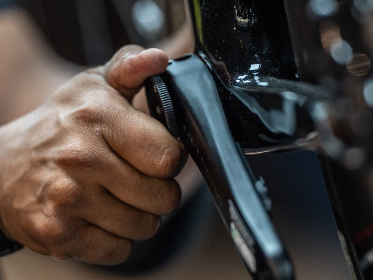 Close up of a hand tightening a bottom bracket on a bicycle using a tool