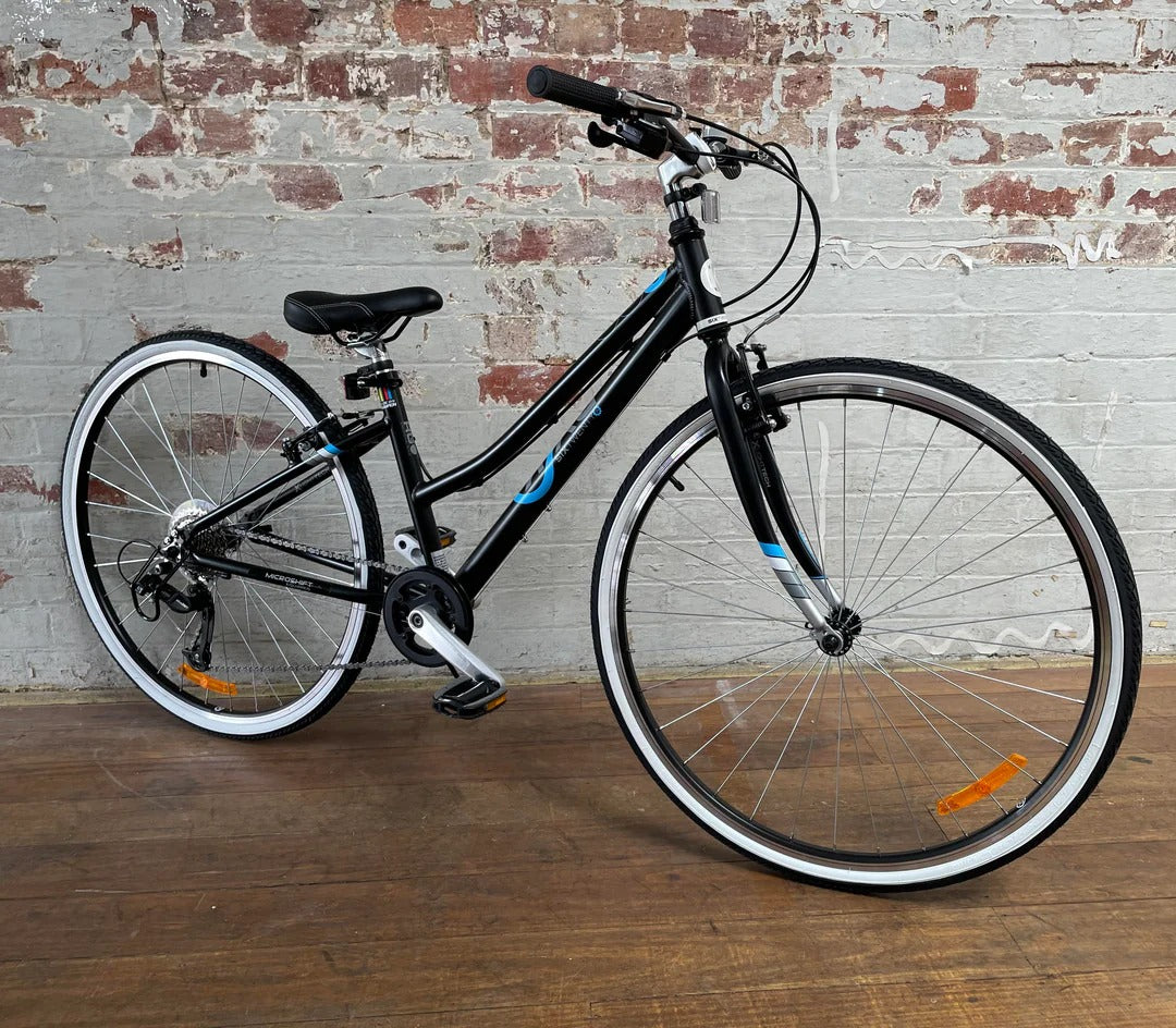 Black bicycle with blue accents and white rims against a brick wall.