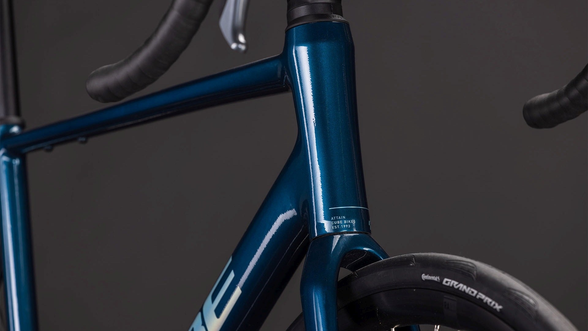 Close-up of a blue road bike frame with 'Cube' branding on a dark background