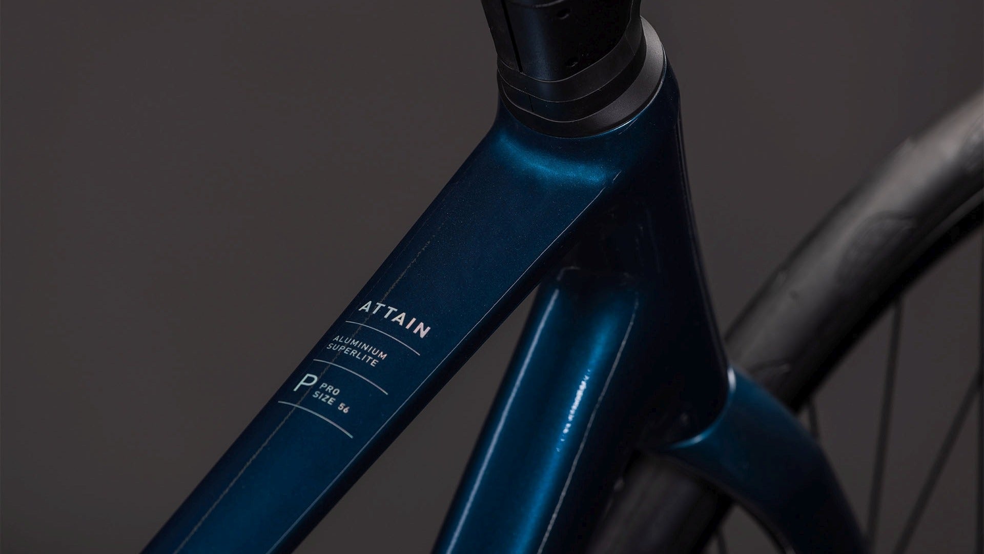 Close-up of aroad bike frame with 'Attain' branding on a dark background
