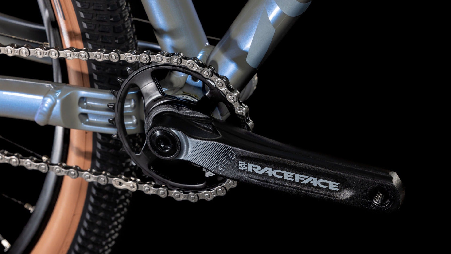 Close-up of a bicycle chain and gear system with 'RaceFace' branding on a black background