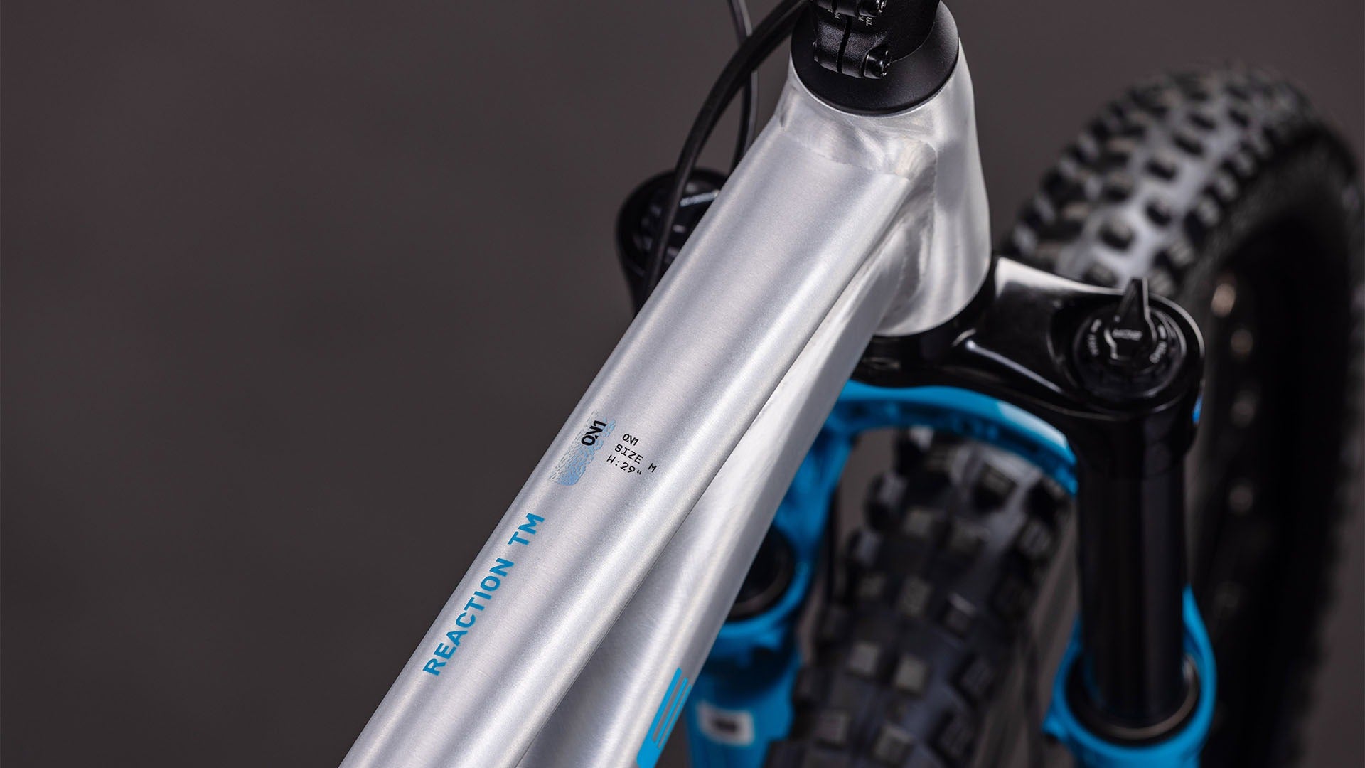 Close-up of asilver mountain bike frame with visible branding on a dark background