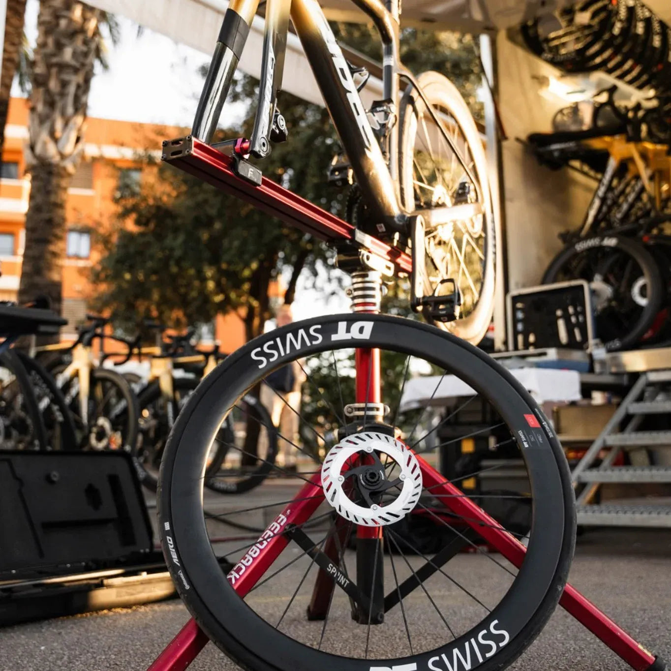 Close-up of a DT Swiss Wheel leaning against a bike stand with bikes in the background