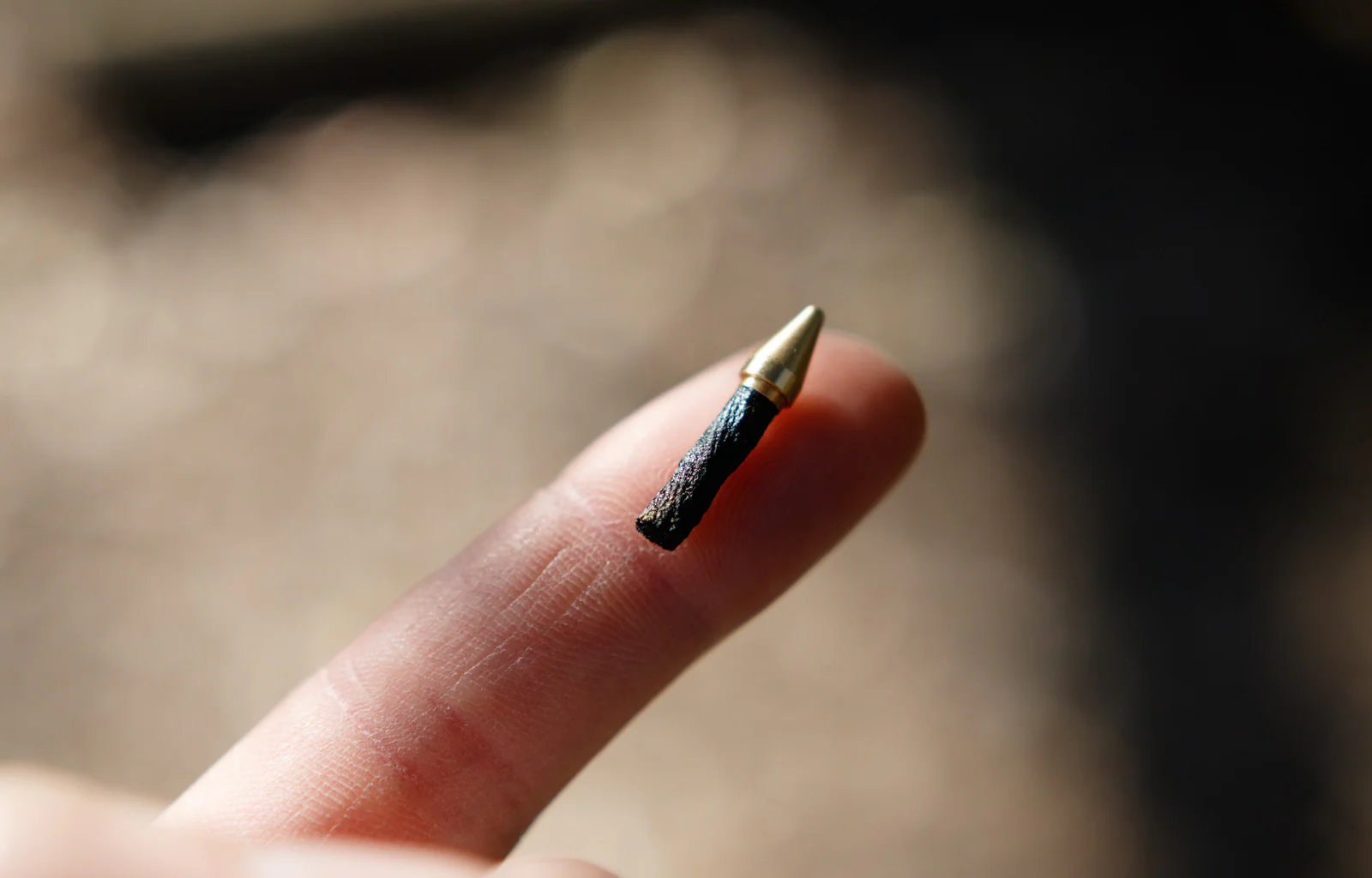 Small bicycle tubeless plug for repairing tubeless tyres sitting on a person's finger with a blurred background