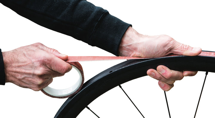 A picture of somone installing the Effetto Carogna Tubular Glue Tape onto a bicycle rim