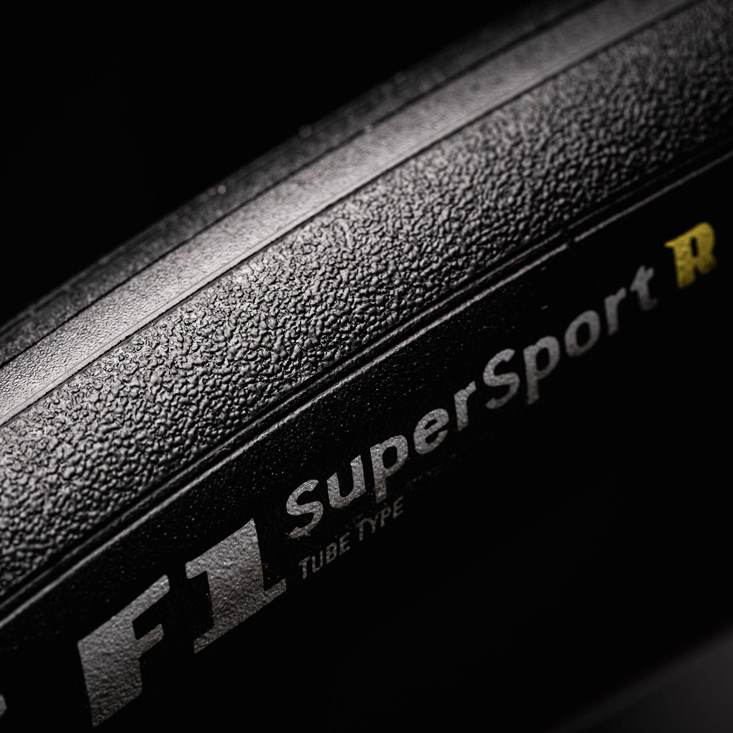 Close-up of a road bike tyre with 'F1 SuperSport R' branding on a dark background
