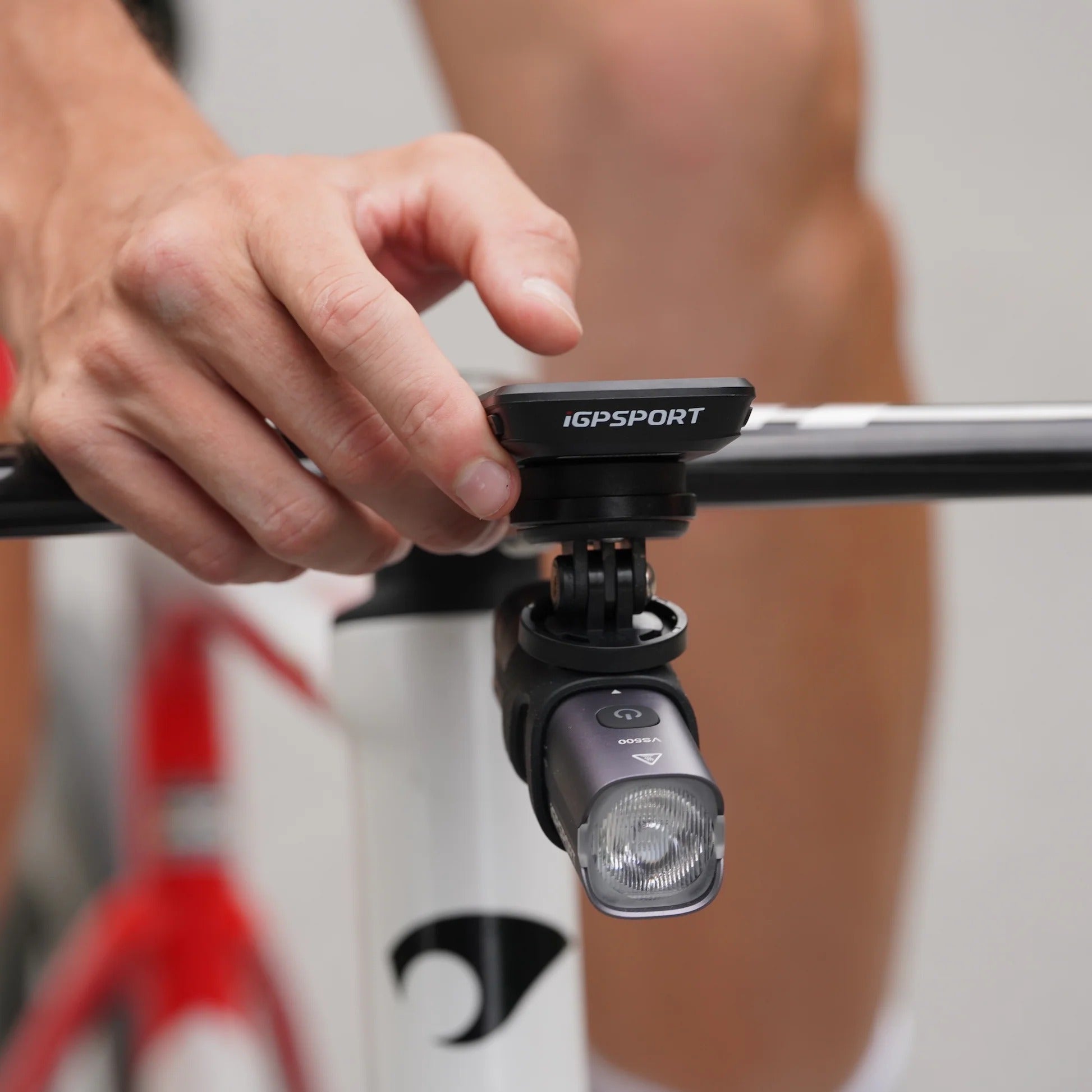 Person holding a cycling IGPSPORT GPS computer on a bicycle handlebar with a blurred background