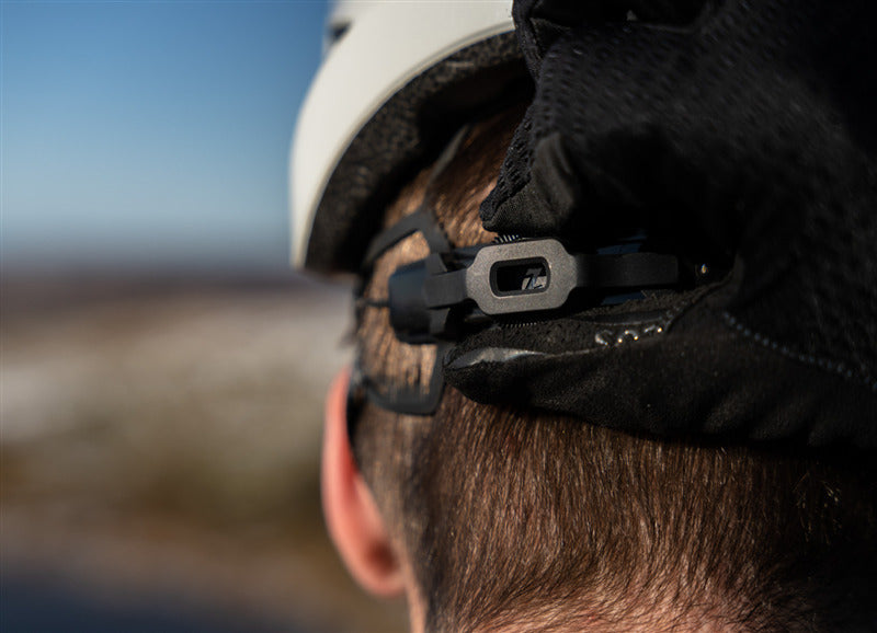 A picture of the Lazer Tonic Kineticore White Helmet on a man's head and he is adjusting the fitting