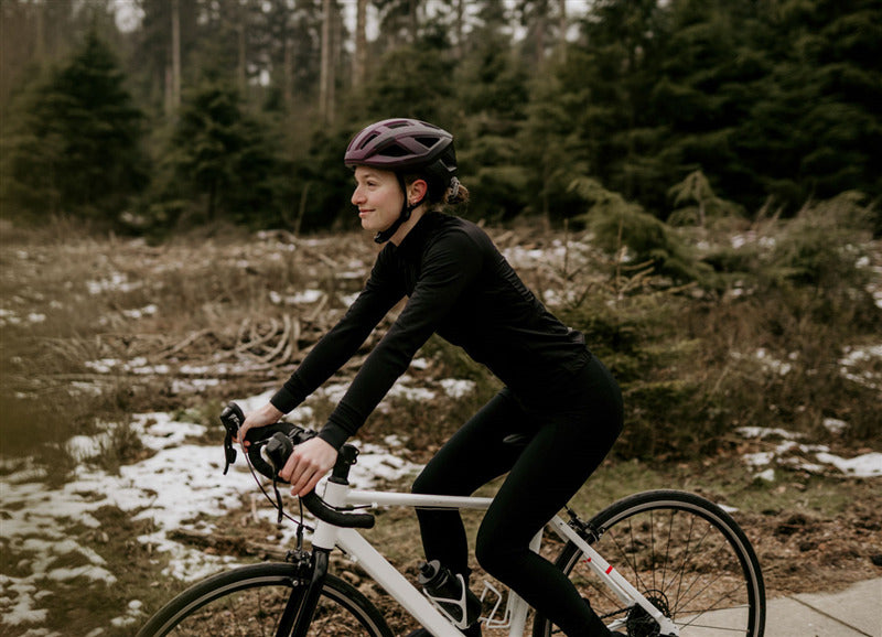 A picture of a lady riding a road bike and wearing a Lazer Tonic Kineticore Helmet