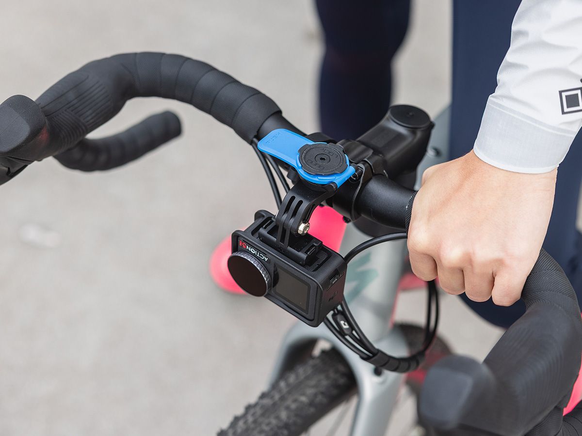 Bicycle handlebar with a camera mounted on it, held by a person.