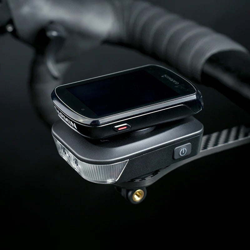 Ravemen FR500 Front Bicycle Light attached underneath a Garmin on a road bike out front mount against a blurred dark background