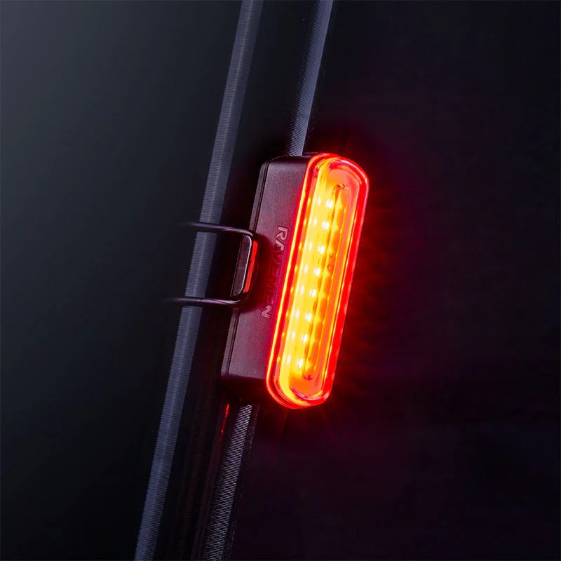 Red rear LED bicycle light attached to the seatpost of a bicycle on a dark background