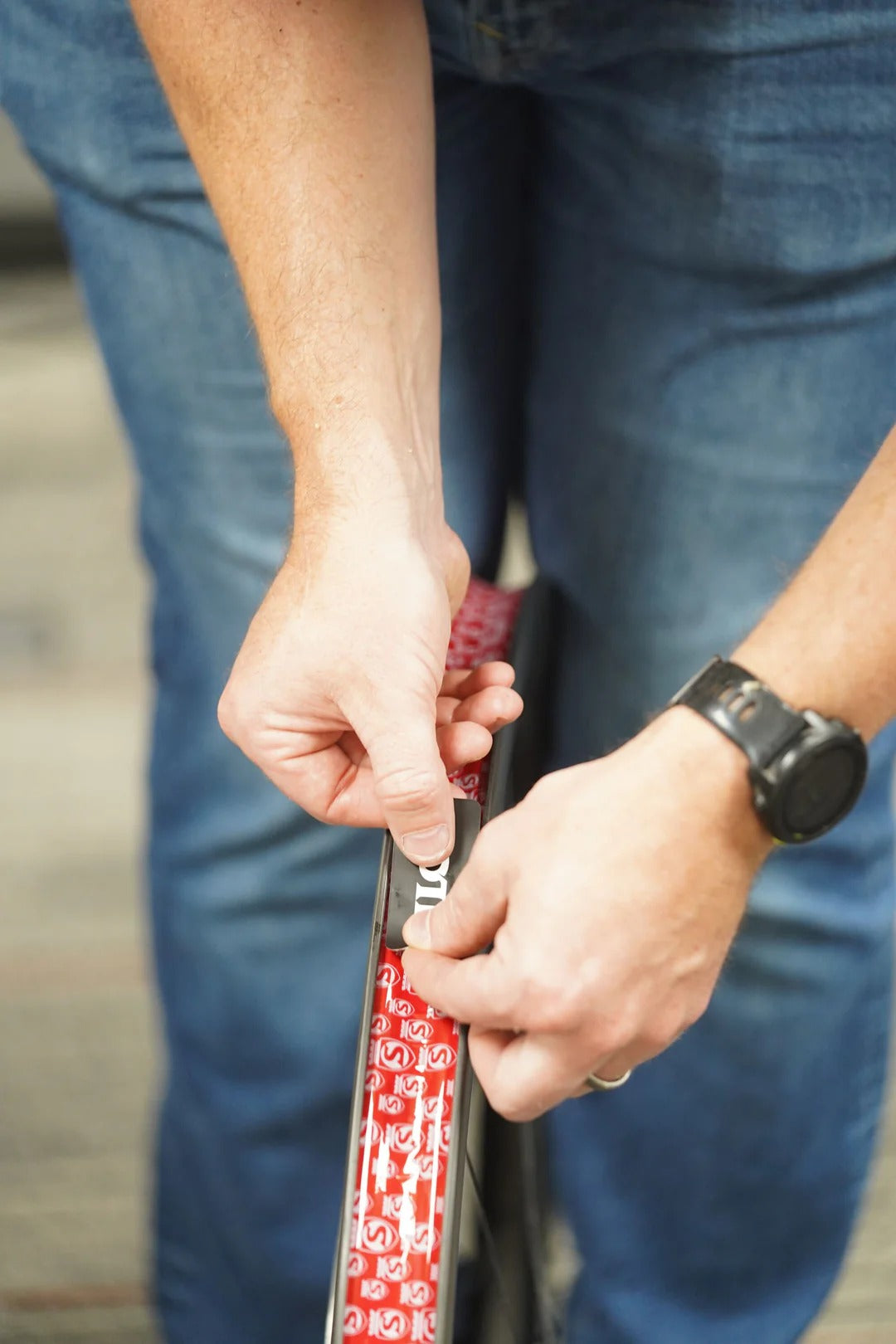 Close-up of hands installing tubeless rim tape on a mountain bike wheel on a blurred background