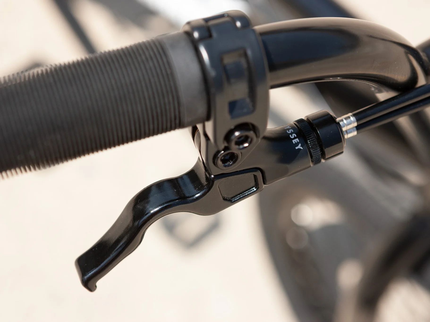 Close-up of aBMX Bike handlebar with brake lever and black grip on a blurred background.