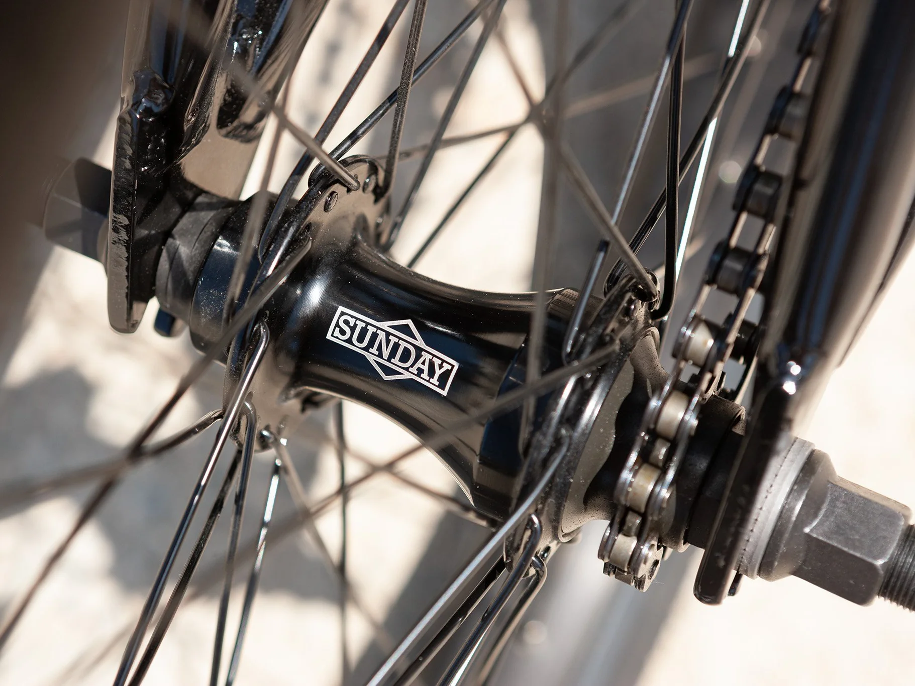 Close-up of a BMX Bike chain and gear system with 'SUNDAY' branding on the rear hub.