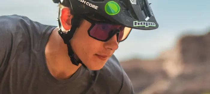 Person wearing a mountain bike helmet and sunglasses with a blurred natural background