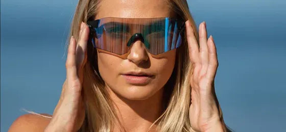 Person wearing reflective sunglasses with a clear blue sky background