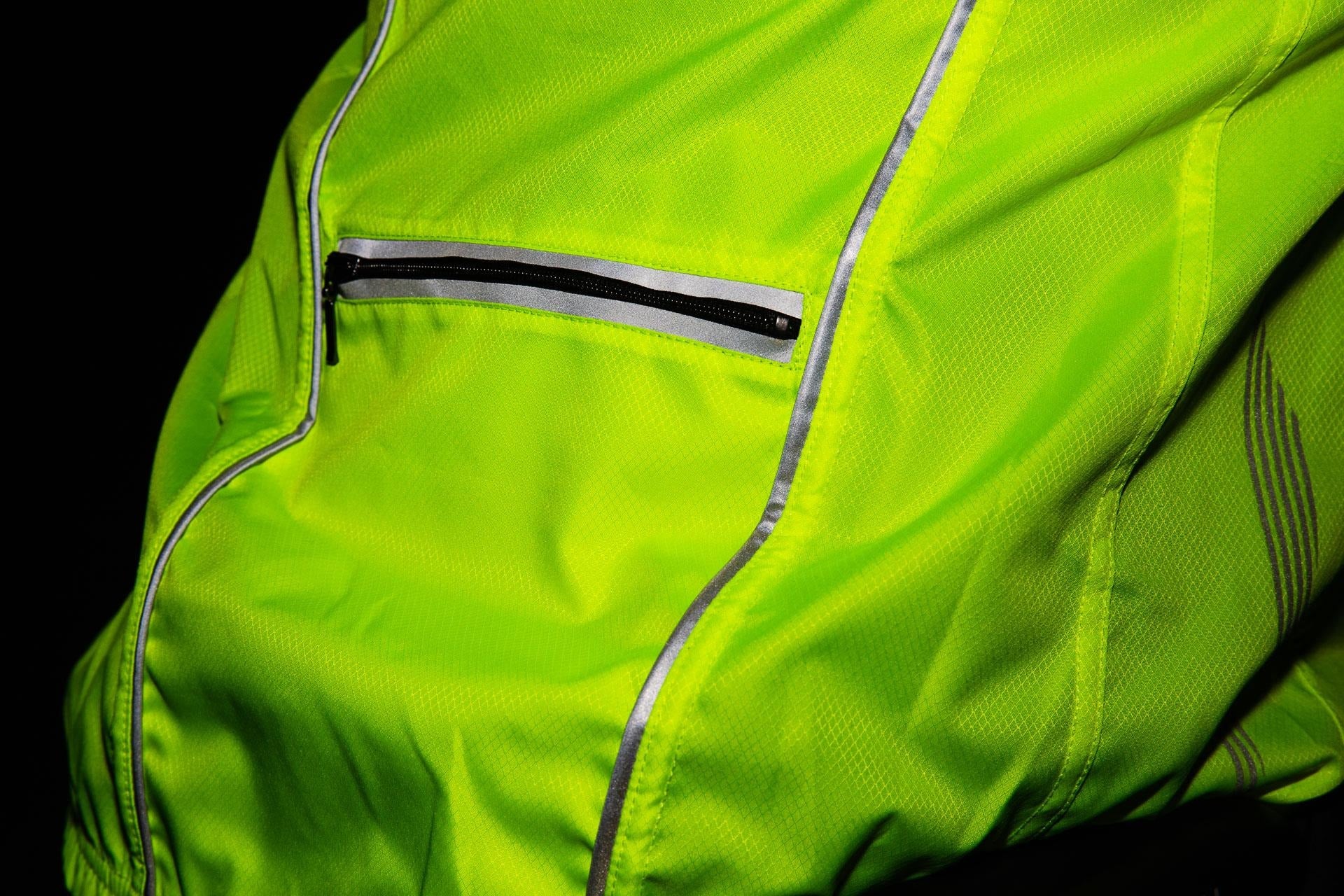 Close-up of a bright green jacket with reflective stripes on a black background