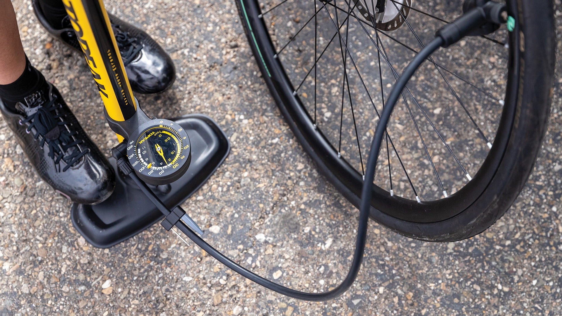 Bicycle pump being used to inflate a bike tyre on a concrete surface
