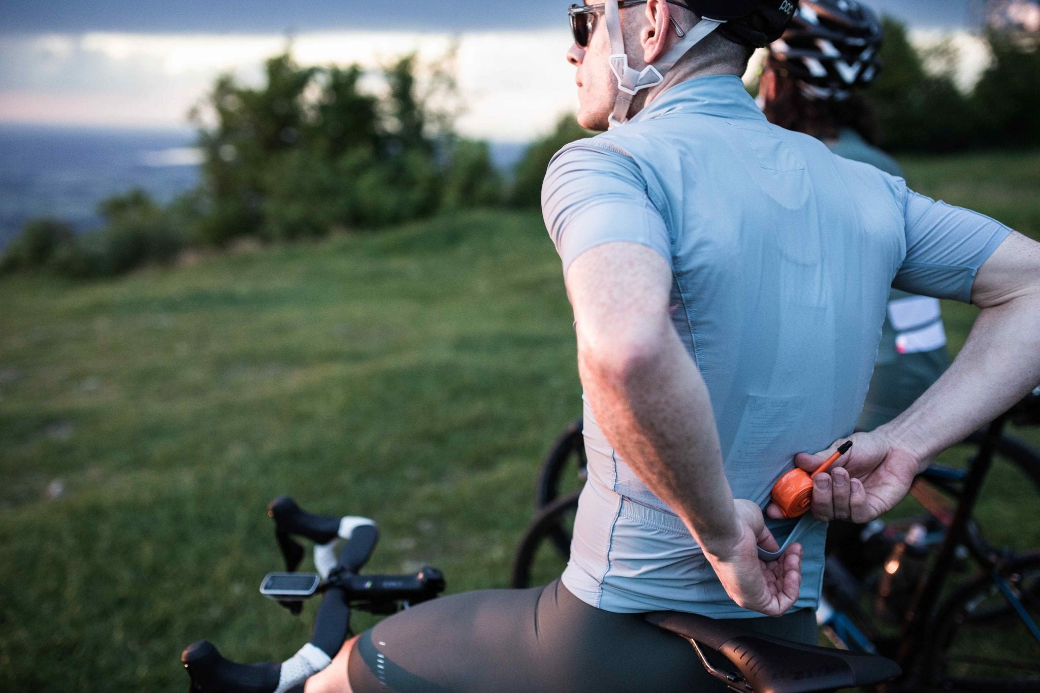 A cyclist putting an orange TPU tube into the back pocket of his cycling jersey