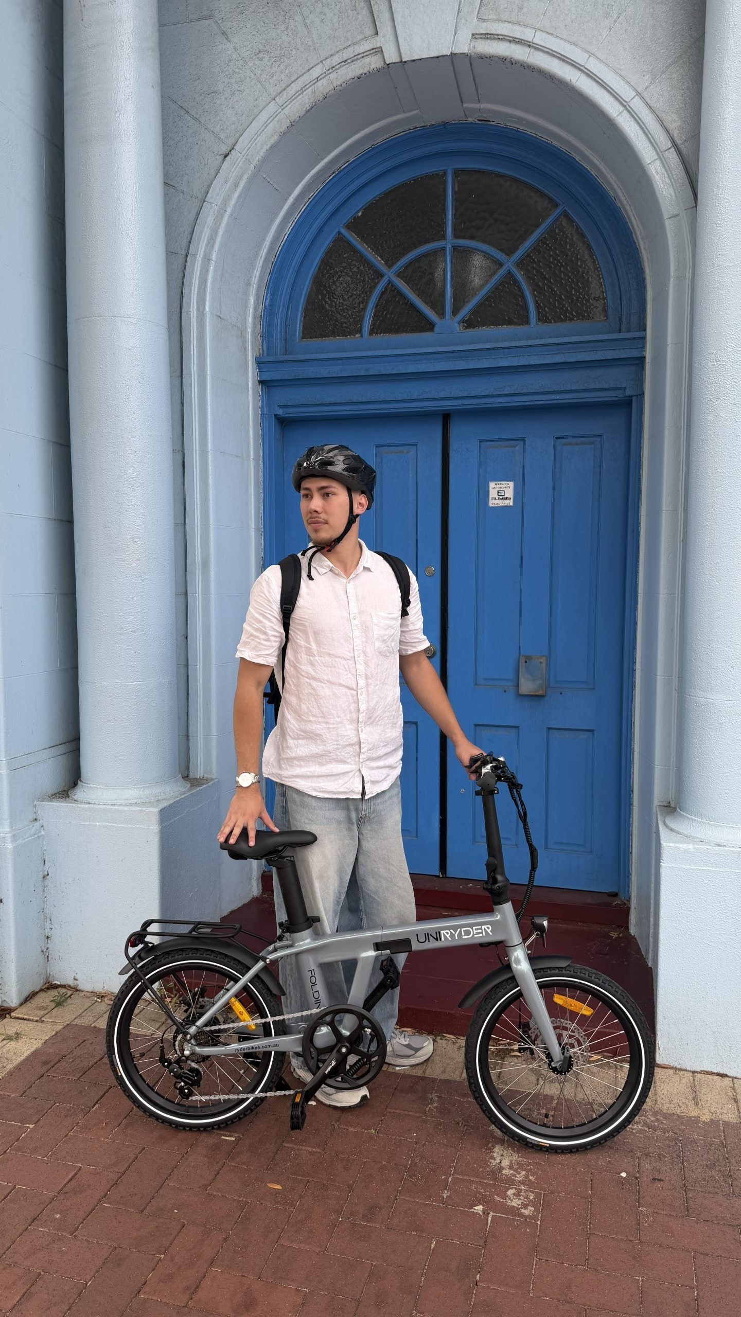 Man with a gray Uniryder bicycle in front of a blue door