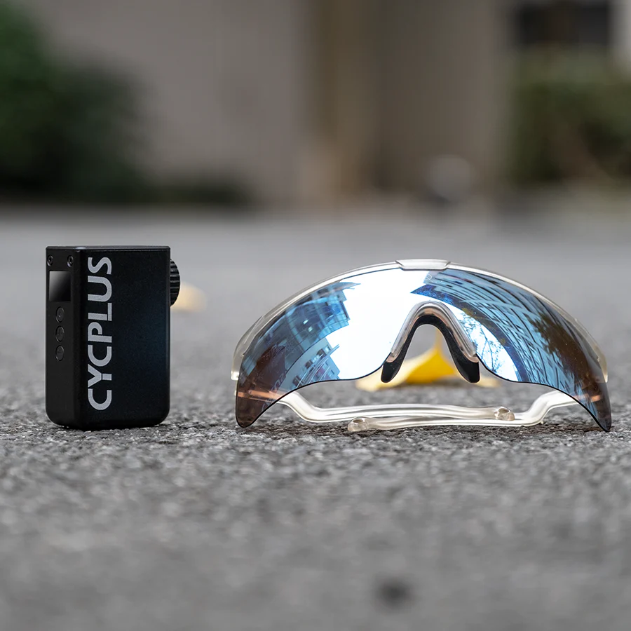 CYCPLUS electric bike pump next to reflective cycling sunglasses on a concrete surface