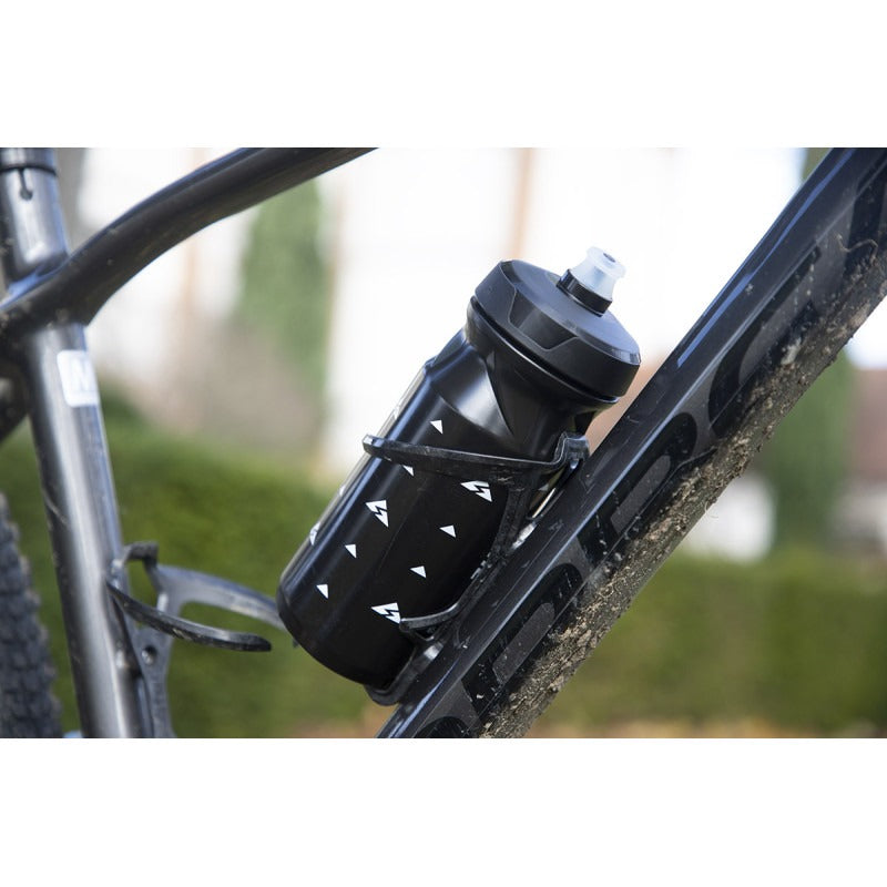 Bicycle water bottle in a bottle cage attached to a bike frame with a blurred outdoor background