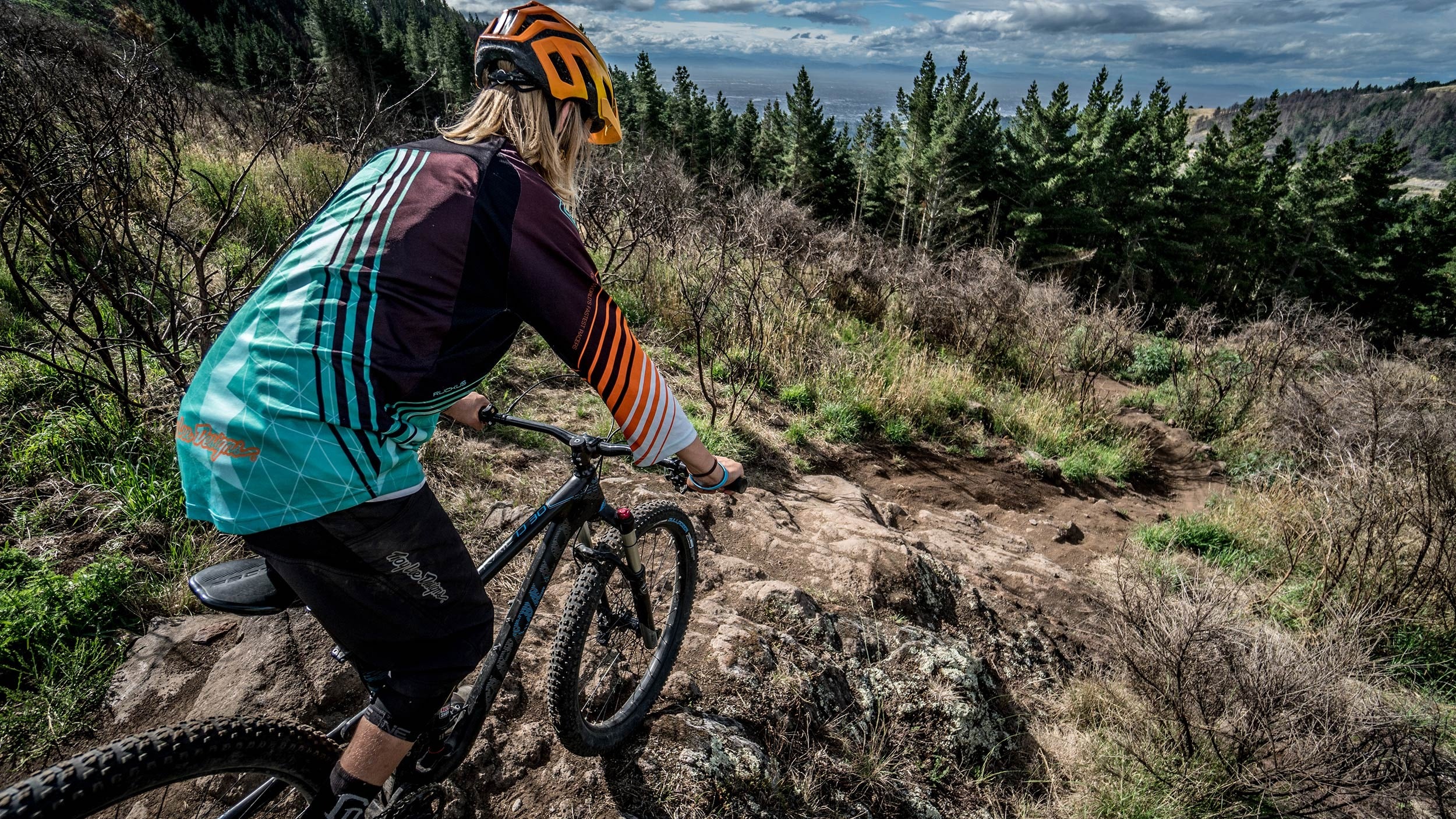 Person riding a mountain bike on a rocky trail with a scenic background