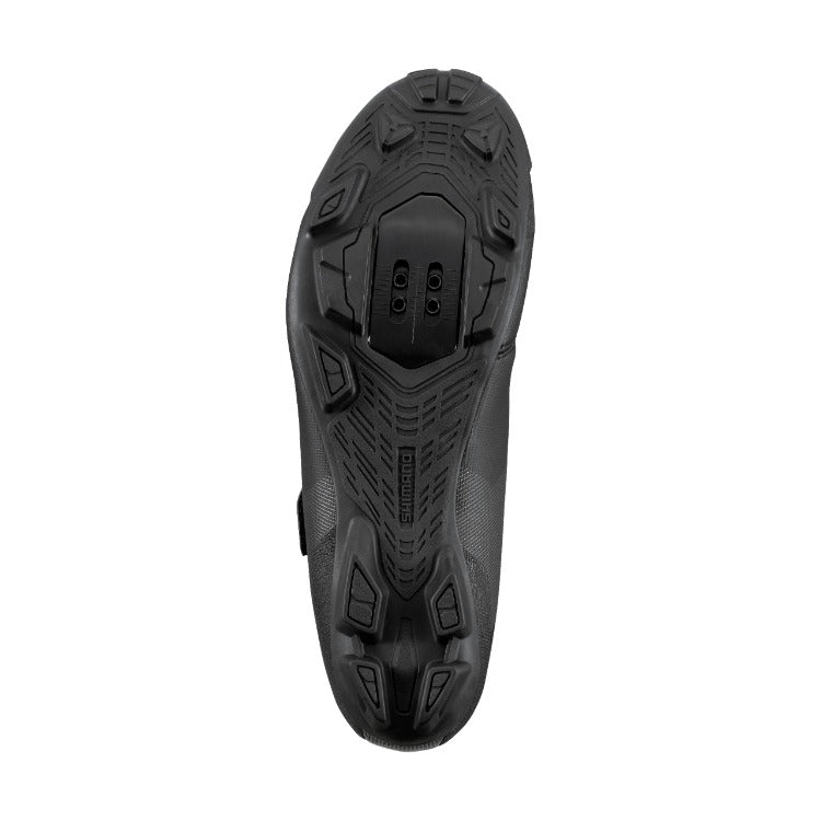 Black mountain bike shoeshoe sole with tread pattern and showing the cleat bolts on a white background