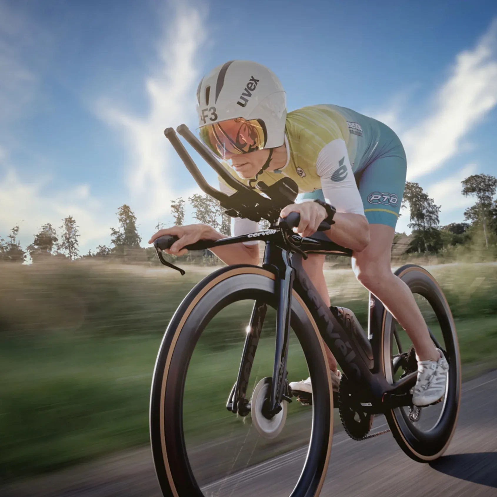 Cyclist in a racing suit riding a bicycle on a road with trees in the background