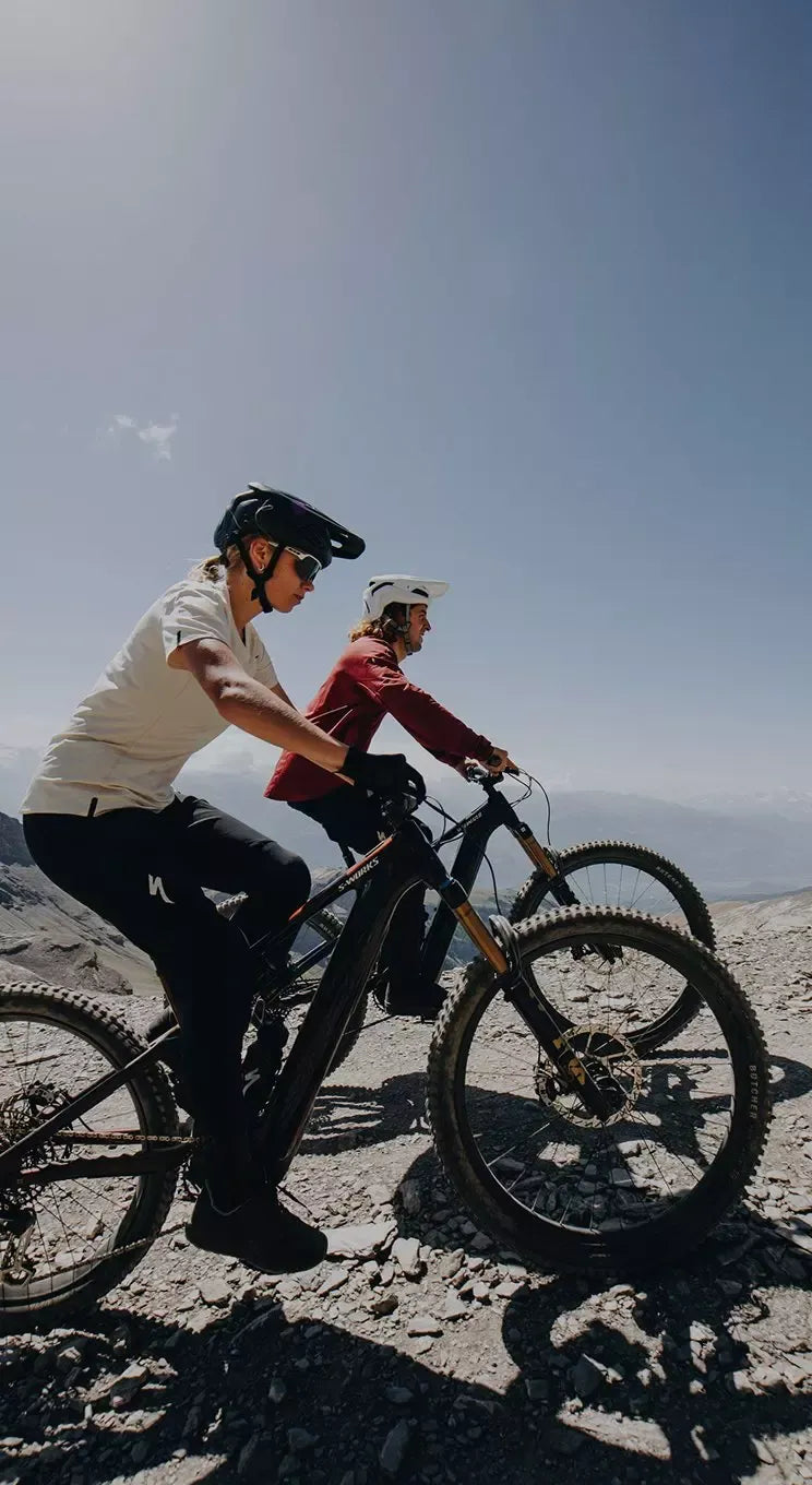 Two people on bicycles against a clear blue sky