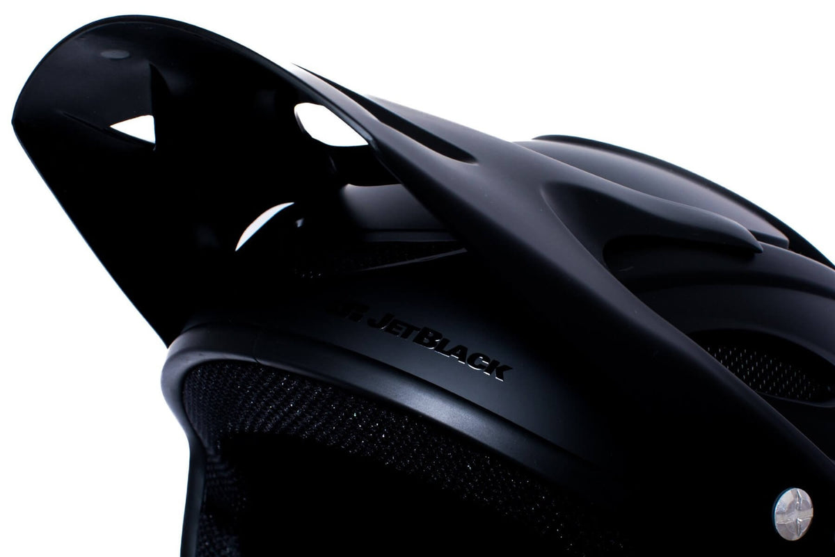 A close up of a visor of a black full face mountain bike helmet on a white background