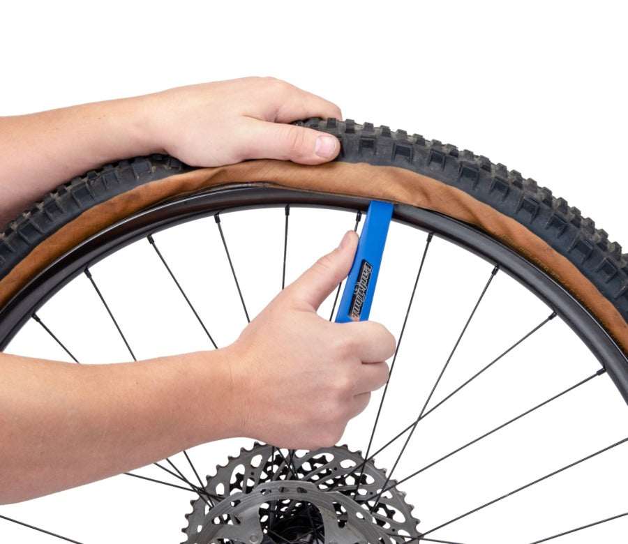 Person using a tool to remove a tyre with a white background