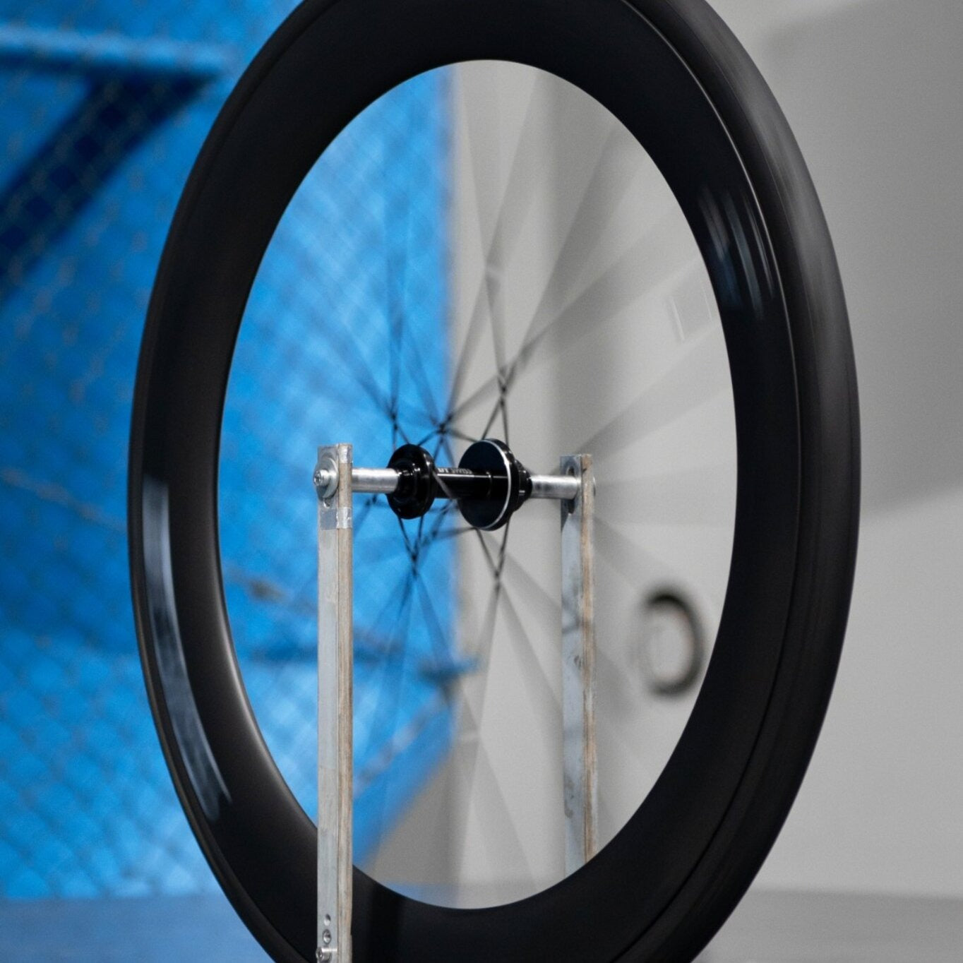 Close-up of a bicycle wheel spinning in a trueing stand with a blurred blue and gray background
