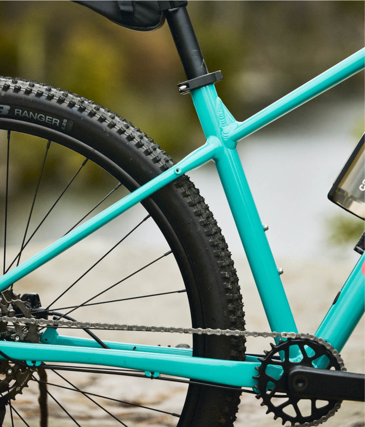 Close-up of a turquoise mountain bike with a blurred natural background