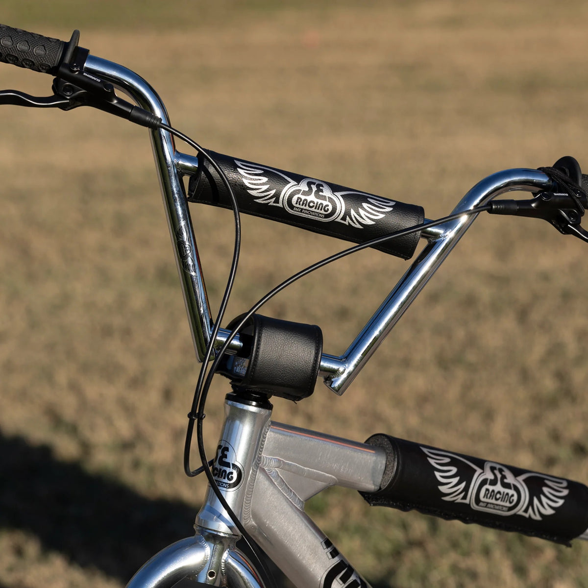 Close up of the handlebars on a silver street cruiser bike with a blurred grass in the background