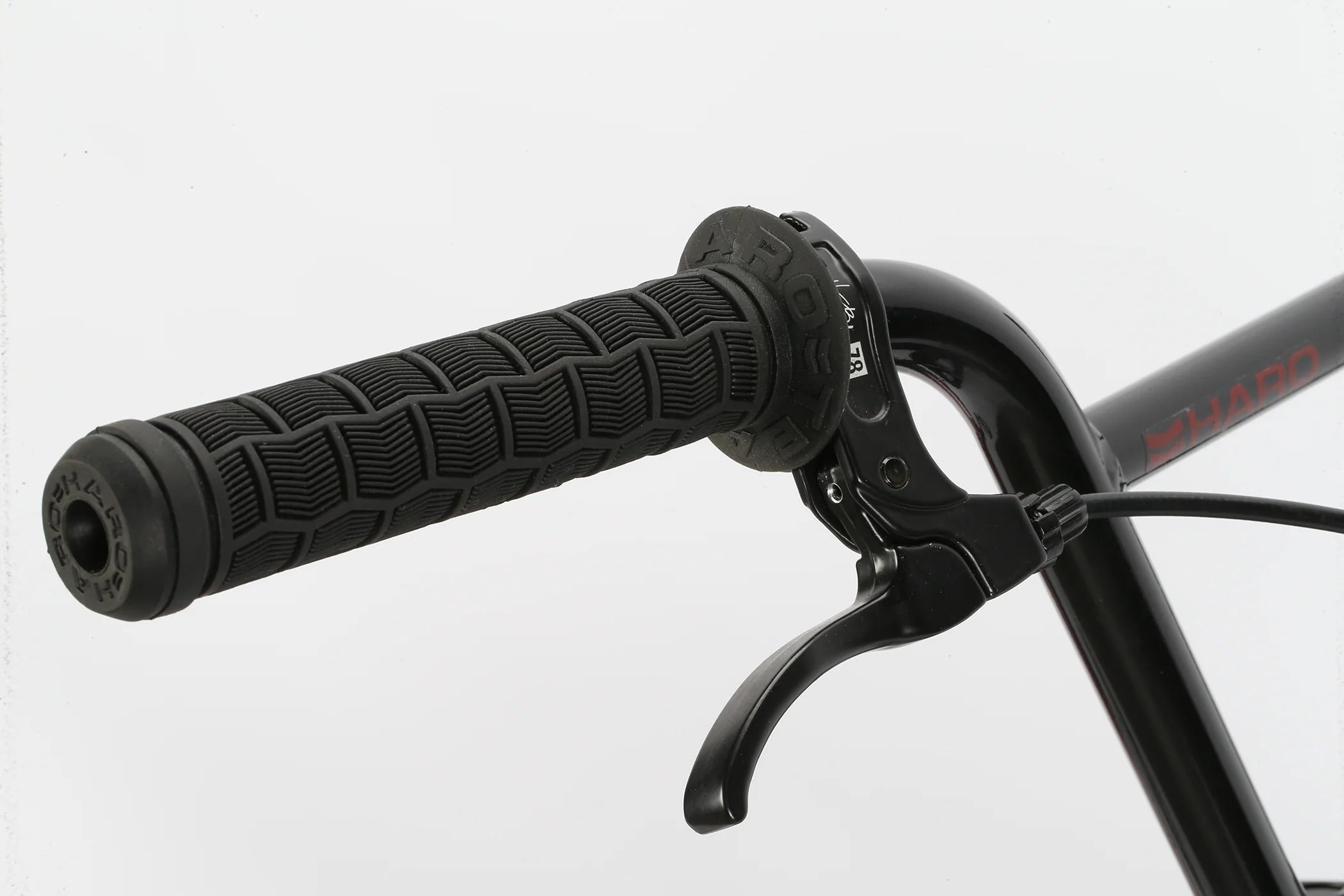 Close-up of a Haro BMX bicycle handlebar with black grips and brake lever on a light gray background