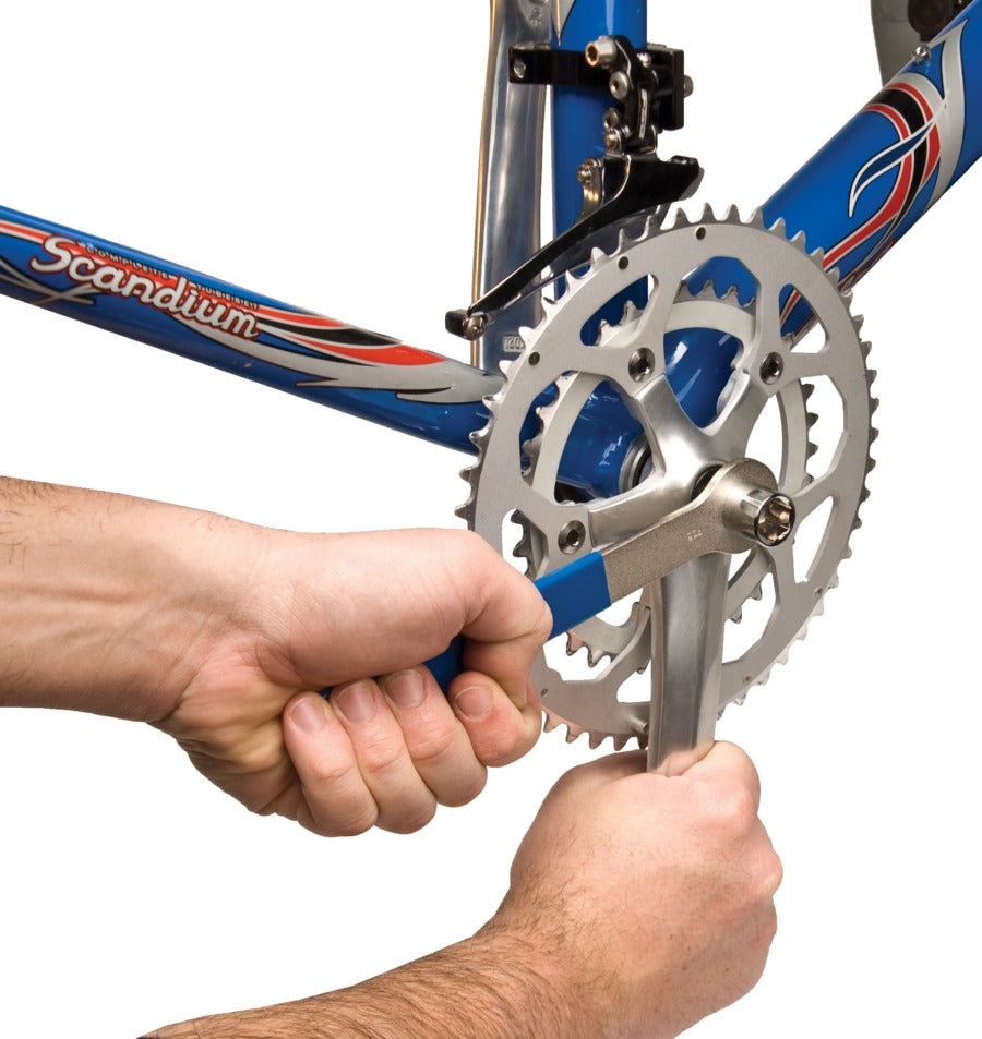 Person installing a crank on a bicycle using a wrench on a white background