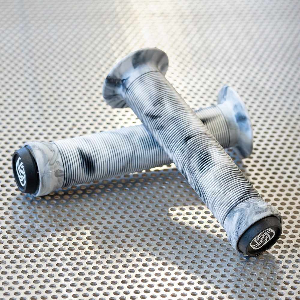Two bicycle handlebar grips with a silver and black marbled design, resting on a perforated metal surface
