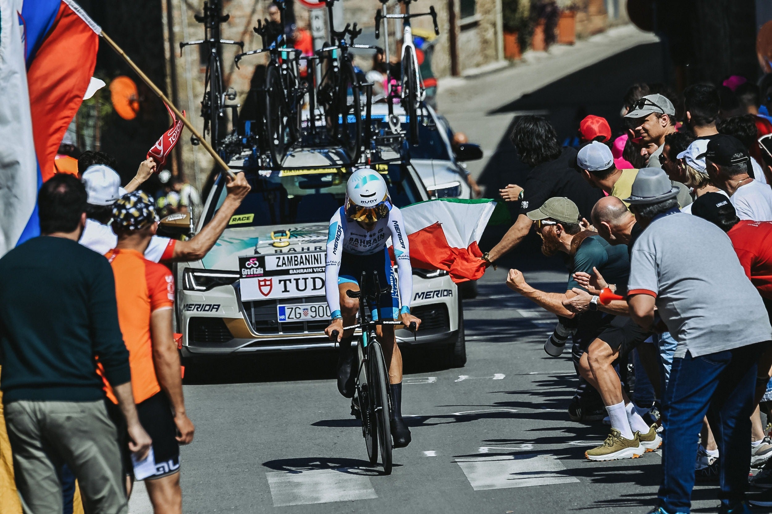 Cyclist in a race with fans and officials on a street