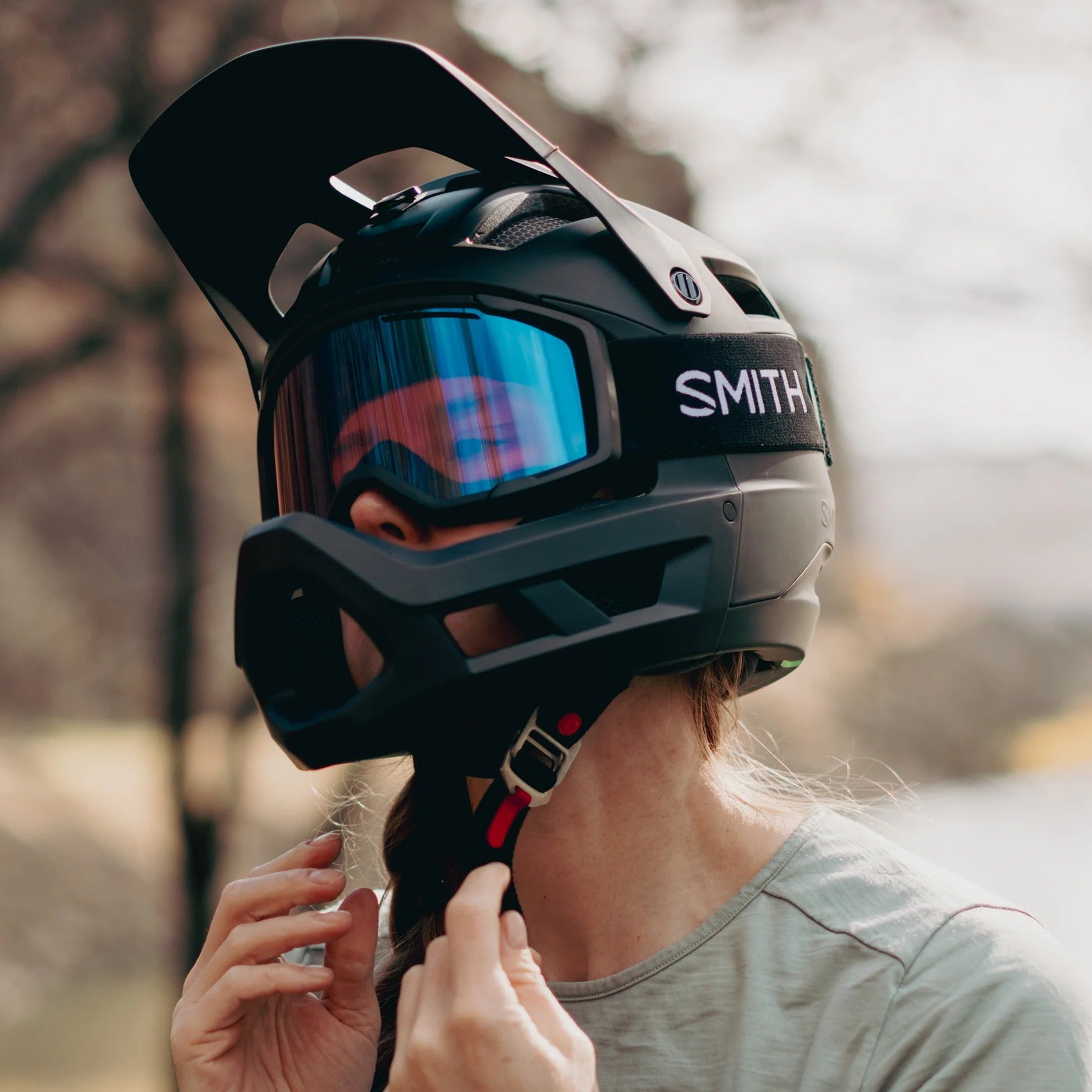 Person wearing a black Smith mountain bike helmet with a visor outdoors