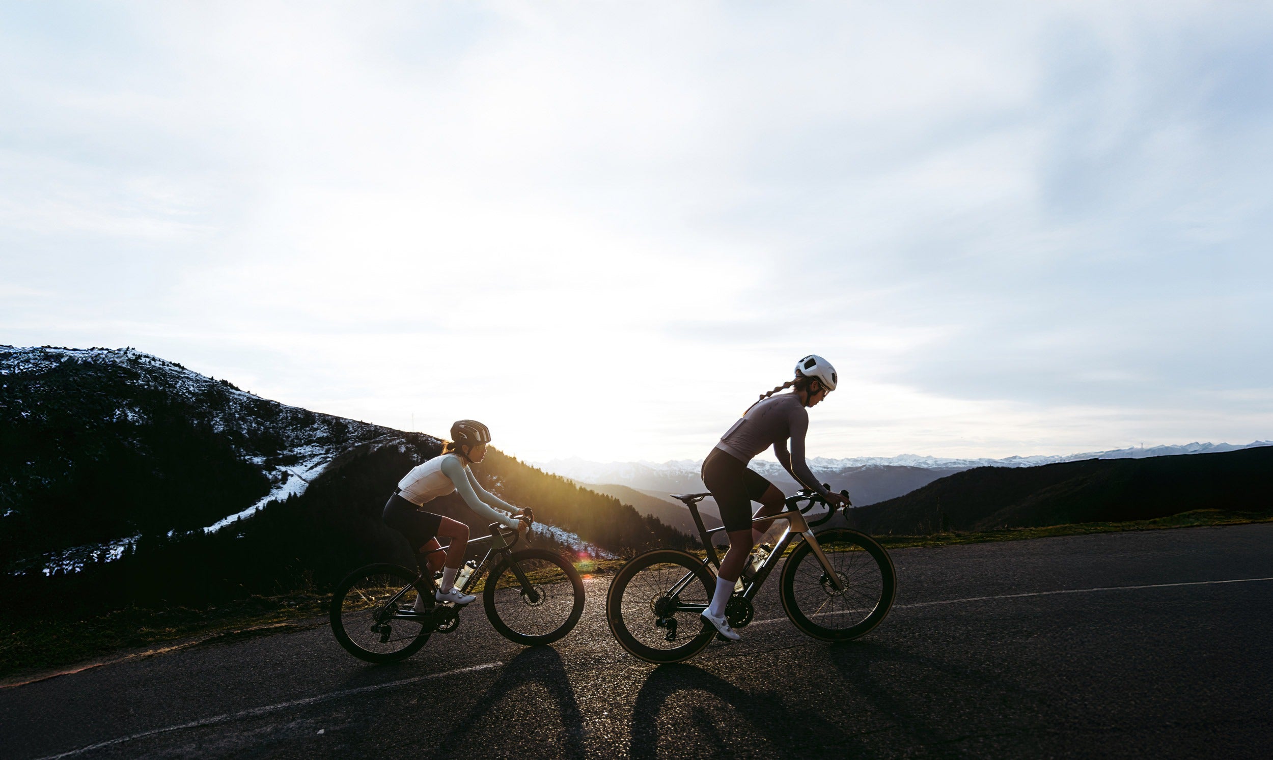 Two cyclists riding on a mountain road with a scenic background