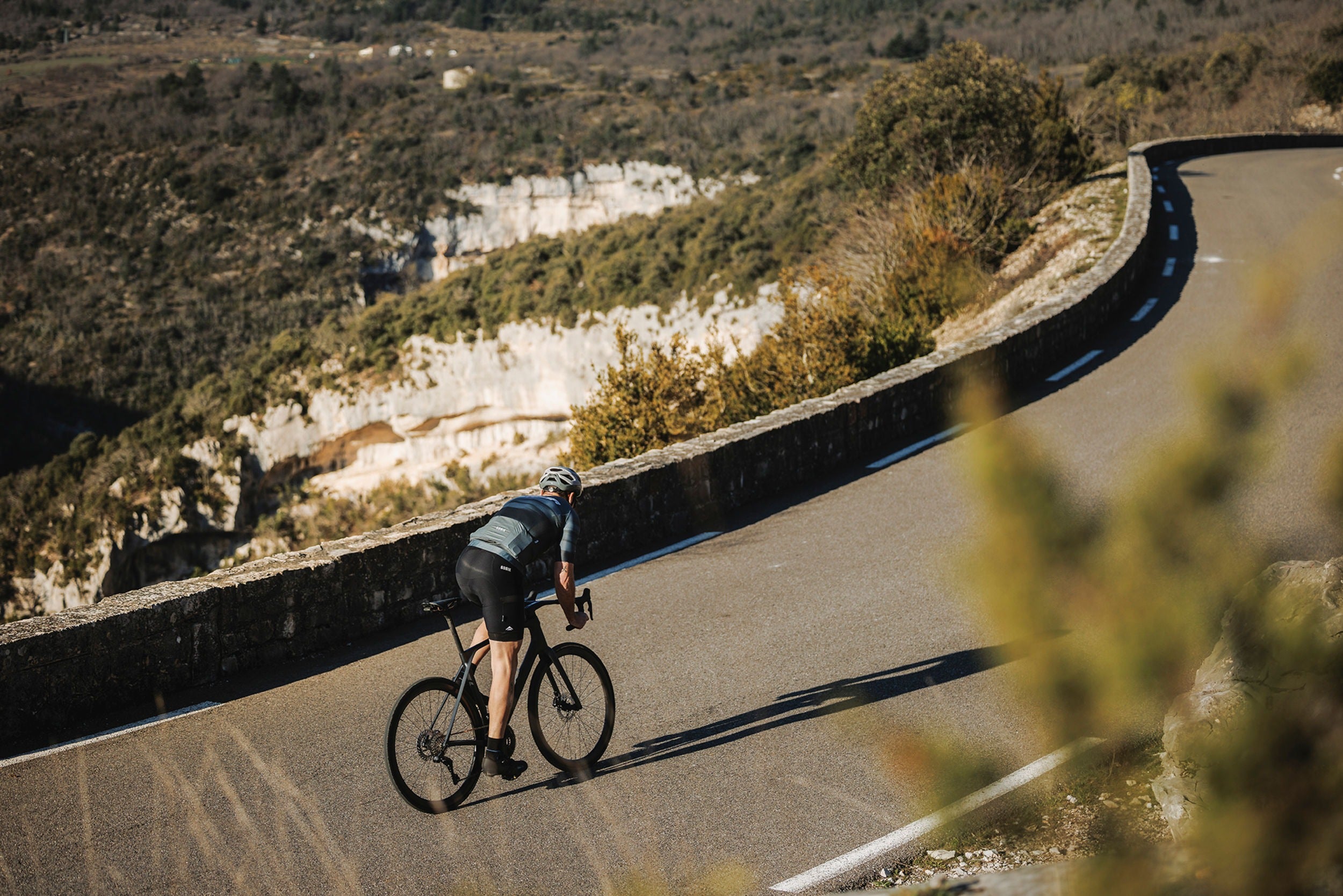 Cyclist riding a road bike on a winding mountain road with scenic views